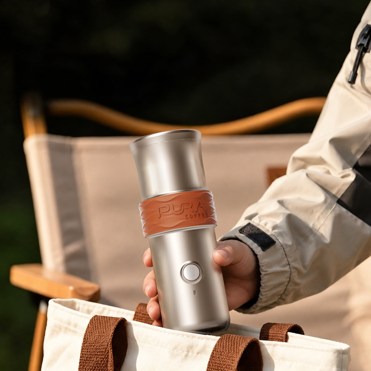 Hand taking the PURA NEO Pro portable espresso machine from a tote bag at a campsite